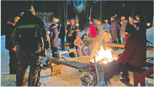 Lantern lit snowshoe hikers enjoy evening